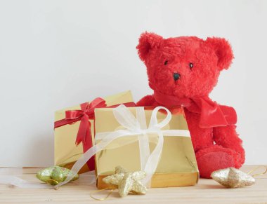 Oyuncak ayı ve ahşap tahta ve beyaz arka plan üzerinde yıldız ile altın hediye kutuları.