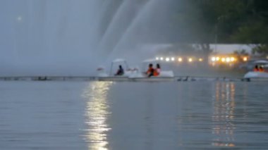 Bulanık insanlar parkta ördek teknesine biniyor.
