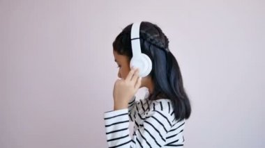 Beyaz kulaklık kullanarak müzik dinleyen ve müziğin ritmine göre sallanan çocuklar