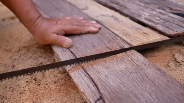 地面に古い木材をソーイング手をクローズアップ — ストック動画
