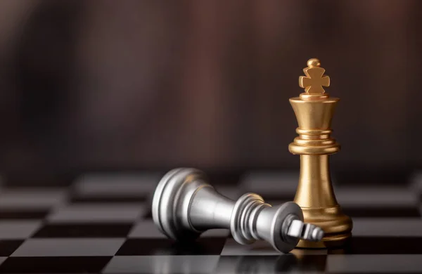 Rei de ouro de pé e prata caindo no tabuleiro de xadrez — Fotografia de Stock