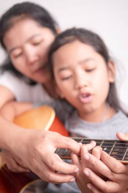 Küçük bir kız anne ile gitar oynuyor