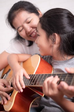 Anne ve kızı bir gitar oynuyor