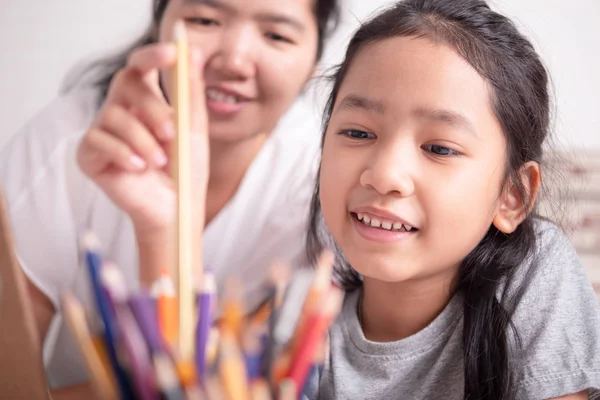 Asiática niña escogiendo un lápiz de color oro — Foto de Stock