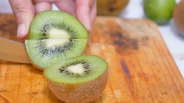 Bıçak kullanan kadınların elleri mutfakta kiviyi tahta tahtada parçalara ayırdı.