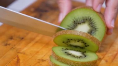 Bıçak kullanan kadınların elleri mutfakta kiviyi tahta tahtada parçalara ayırdı.