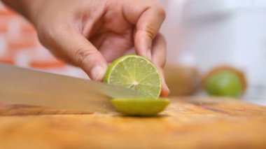 Bıçak kullanan kadınların elleri, yeşil limonu mutfaktaki tahta tahtada parçalara ayırdı.