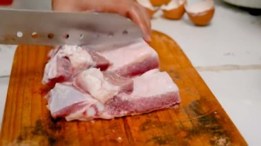 Mutfakta kesme tahtası üzerinde parçalarhalinde kesilmiş domuz eti kullanarak kadınların elleri