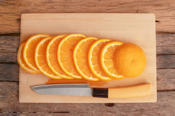 Orange fruit sliced and the knife on the cutting board
