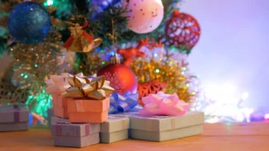 Noel topları ve altın çan ahşap masa üzerinde grup hediye kutusu yer ile ağacın altında çam ve reindeer asılı. Kopyalama alanı ile yanıp sönen ışık ve bulanık arka planlar.