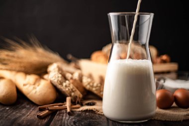 Sütü torbaya konmuş cam bir şişeye dök. Bir sürü ekmek ve yumurta ahşap bir masada yatıyordu..