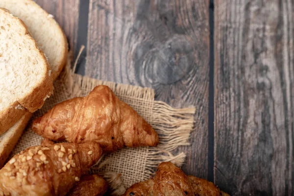 クロワッサンと全粒小麦パンの袋に木製のテーブル — ストック写真