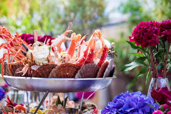 Zeevruchten schotel en bloemen op restaurant tafel — Stockfoto