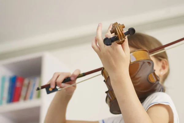 Girl playing violin in white room