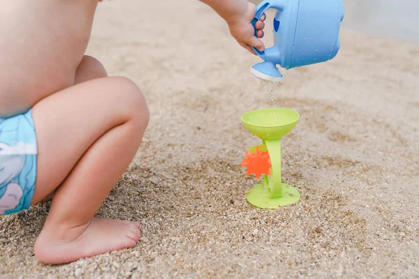 Niño jugando con la regadera de juguete en la playa — Foto de Stock