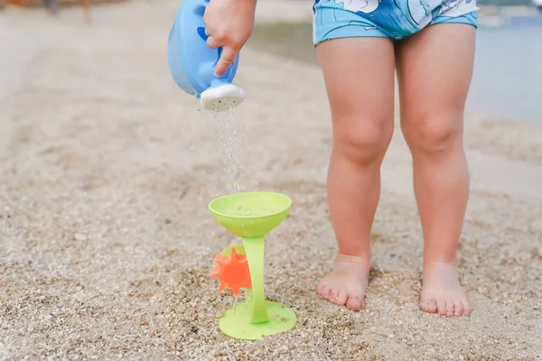 Kind spielt mit Spielzeug-Gießkanne am Strand — Stockfoto