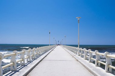 Denize, uzun iskele başlığında mavi gökyüzü ile güneşli bir gün.