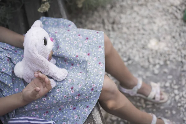 Kind meisje met een zacht stuk speelgoed op schoot buiten — Stockfoto