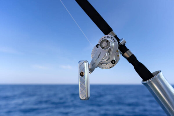 Fishing rod in a saltwater motor boat during fishery day in blue ocean. Successful fishing concept