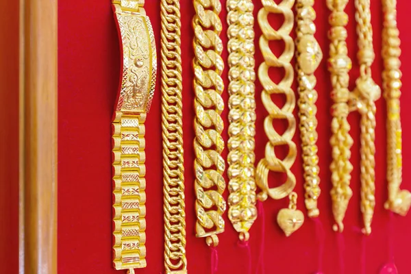 Luxury gold bracelets on red flannel background, beautiful golds is pendant ornament accessory asian style.