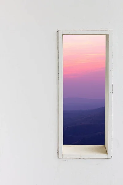 White wall window with sunset mountain view, vertical landscape concept background.