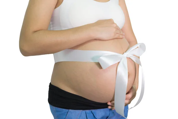 妊娠中の女性両手白リボンのギフトと腹腹 分離の白い背景を持つ 健康の概念 — ストック写真