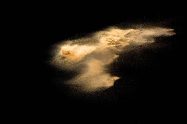 Altın kum patlaması siyah arka planda izole edildi. Soyut kum bulutu. Koyu arka planda altın renkli kum sıçraması. Sarı kum, havada uçan bir dalga..