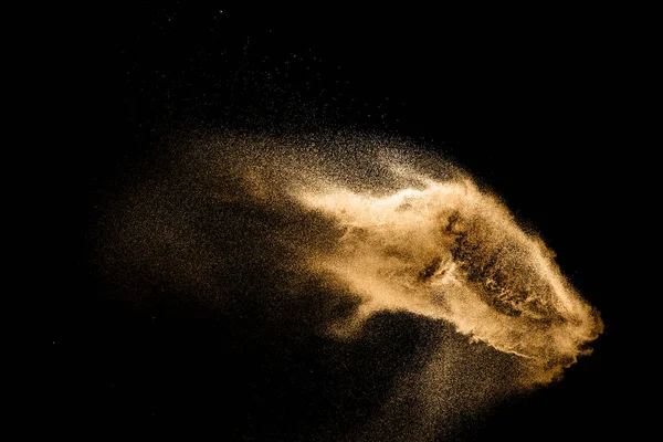 Golden sand explosion isolated on black background. Abstract sand cloud. Golden colored sand splash against dark background. Yellow sand fly wave in the air.