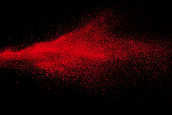 Red color powder explosion on black background.Freeze motion of red dust particles splashing.