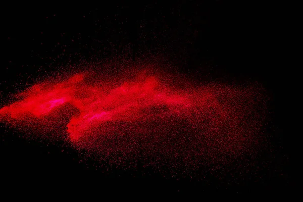 Red color powder explosion on black background.Freeze motion of red dust particles splashing.