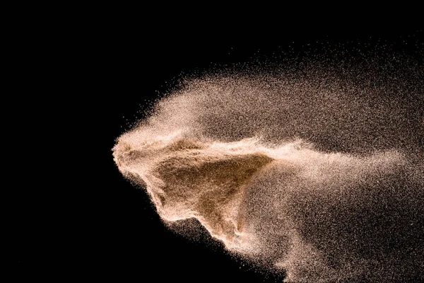 Kuru dere kum patlama. Altın renkli kum sıçrama agianst koyu arka plan.