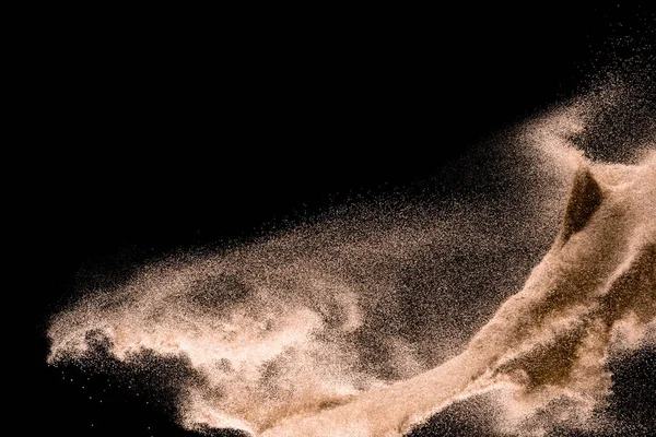 Kuru dere kum patlama. Altın renkli kum sıçrama agianst koyu arka plan.