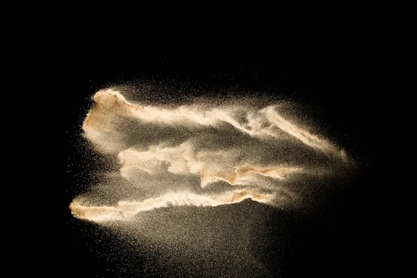 Abstract sand cloud.Golden colored sand splash agianst dark background.Yellow sand fly wave in the air. Sand explode on black background ,throwing freeze stop motion concept.