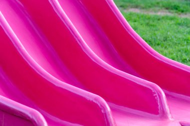 Pembe plastik kaydırak tüneli parktaki çimlerin üzerinde.