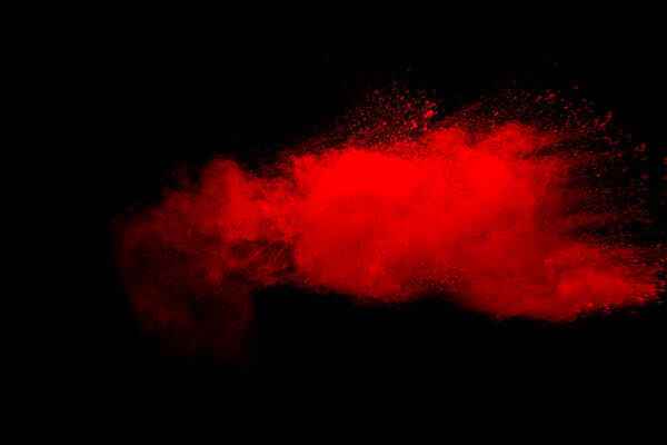 Abstract red dust explosion on black background. Freeze motion of red powder splash.