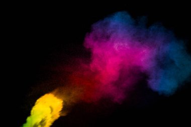 Siyah arkaplanda soyut çok renkli toz patlaması. Renkli toz parçacıklarının hareketsiz hareketi sıçrar. Boyalı Holi.