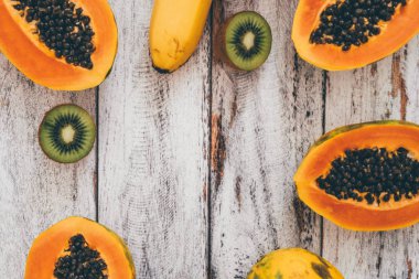 Eski püskü ahşap zemin üzerine bütün mango, muz, dilimlenmiş papaya ve kivi Üstten Görünüm