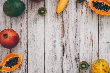 Bütün mango, muz, nar, limon, papaya ve kivi eski püskü ahşap arka plan üzerine dilimlenmiş görünümünü ana sayfa