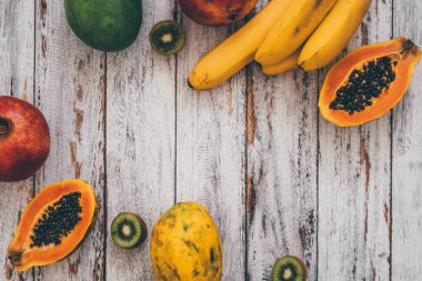 Bütün mango, muz, nar, limon, papaya ve kivi eski püskü ahşap arka plan üzerine dilimlenmiş görünümünü ana sayfa