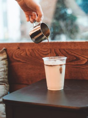 Buz latte kadar yakın ahşap arka plan üzerine sütlü kahve dökme