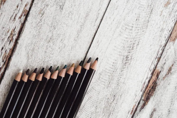Ahşap arka plan üzerinde renkli kömür kalemler grubu
