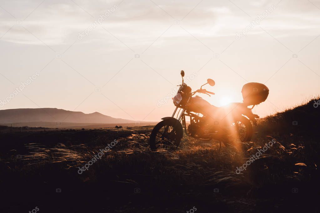 Motobike in susnset sky beams in mountains silhouette