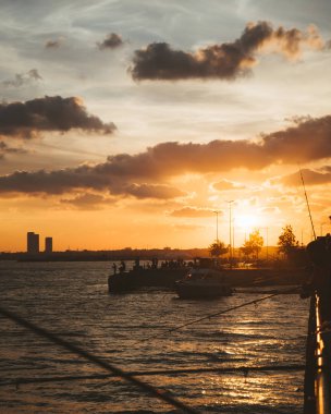 küçük gemilerin kumsalda güneş doğarken ön plan üzerinde balıkçılık çubuklar ile demirleyen