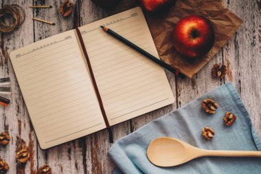 Ahşap ve mavi arka plan üzerinde bir tarif kitabı-elma ceviz ve kaşık yemek