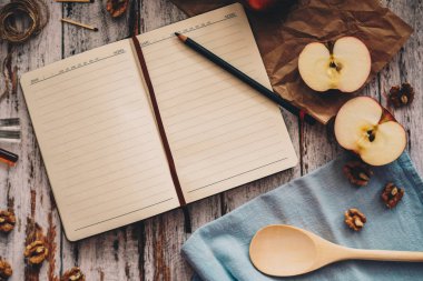 ahşap arka plan üzerinde elma, ceviz ve kaşık ile tarif kitabı