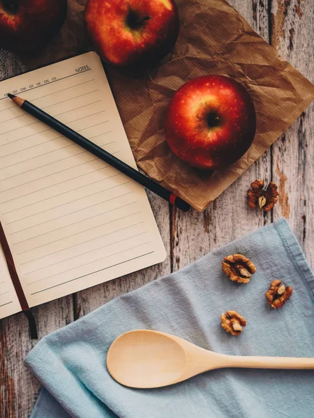 Ahşap ve mavi arka plan üzerinde bir tarif kitabı-elma ceviz ve kaşık yemek