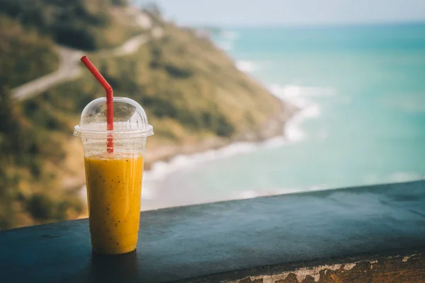 Sekali Pakai Secangkir Smoothie Dengan Jerami Dan Pemandangan Pantai Berbatu Stok Gambar Bebas Royalti