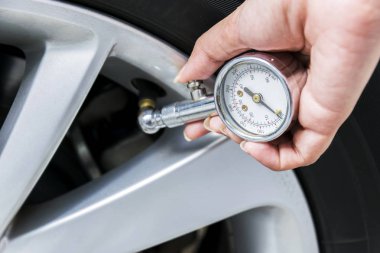 Kadınlar onların lastiği kontrol el ile teknik olarak yetenekli kadın basınç, lastik ölçüm cihazları lastik takılı.