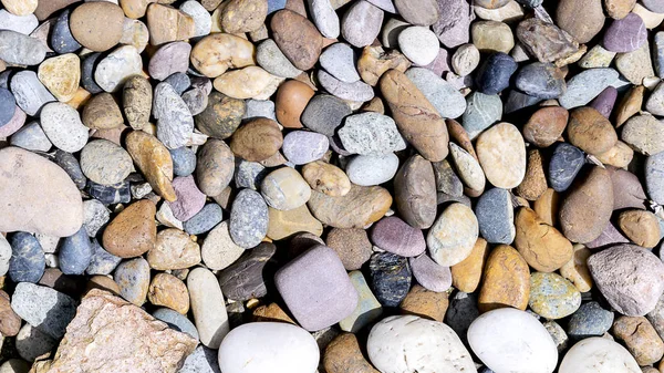 Various colored stones are placed together. In the sun The stones are overlaid over the rocks, there is a large stone on the block, not a small stone.