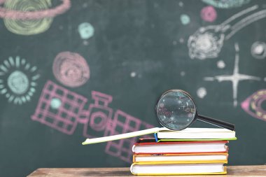 Sınıf atmosferi evrenin okuyor, masanın üzerine bir kitap ve bir büyüteç üzerinde en iyi, yazma yıldız tahtaya.